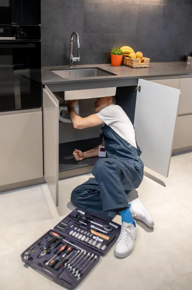 A plumber working under a kitchen sink